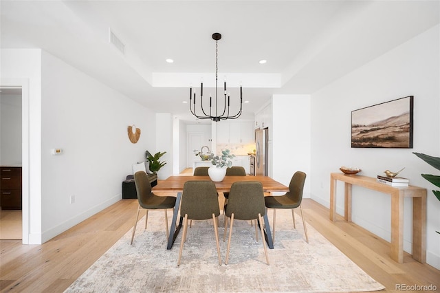 3301 Arapahoe Ave Unit 411, Boulder, CO 80303 - dining room featuring a chandelier, light wood-style floors, recessed lighting, and a raised ceiling