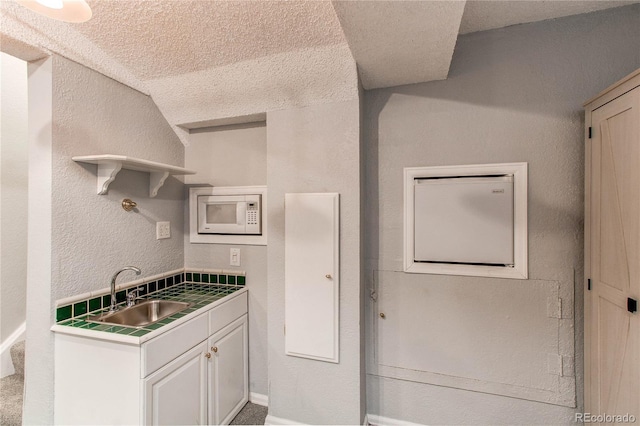 4483 S Fundy St, Centennial, CO 80015 - kitchen with white microwave, open shelves, a textured ceiling, a textured wall, and white cabinetry