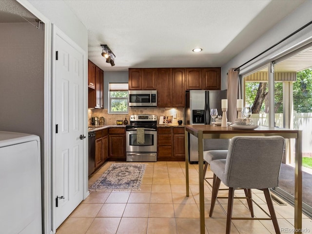 9696 E Kansas Cir Unit 2, Denver, CO 80247 - kitchen featuring appliances with stainless steel finishes, washer / clothes dryer, backsplash, light tile patterned flooring, and recessed lighting