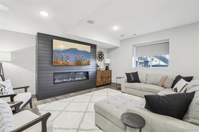 living room featuring wood finished floors, a large fireplace, baseboards, and recessed lighting