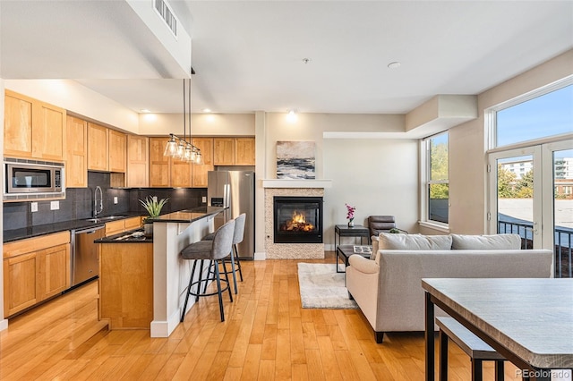 kitchen featuring decorative light fixtures, appliances with stainless steel finishes, light hardwood / wood-style floors, and a center island