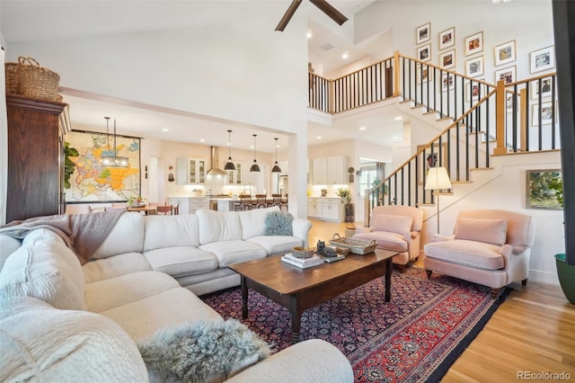 1455 Flowers Ct, Erie, CO 80516 - living room featuring ceiling fan, visible vents, stairway, high vaulted ceiling, and light wood-style flooring