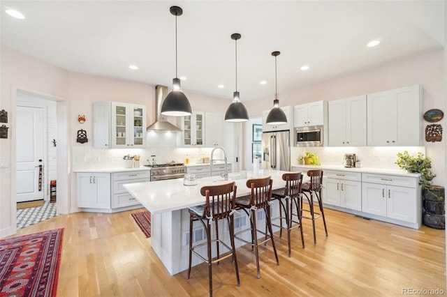 1455 Flowers Ct, Erie, CO 80516 - kitchen with light countertops, light wood-style flooring, wall chimney exhaust hood, stainless steel appliances, and tasteful backsplash