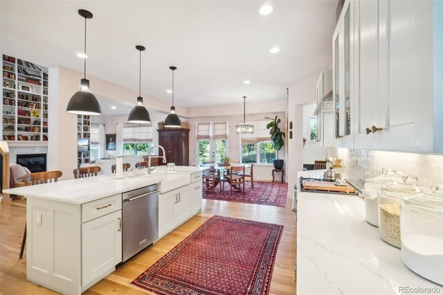 1455 Flowers Ct, Erie, CO 80516 - kitchen featuring stainless steel dishwasher, a kitchen breakfast bar, white cabinetry, light stone counters, and a sink