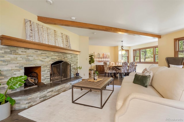 living room with hardwood / wood-style flooring, a stone fireplace, and beam ceiling