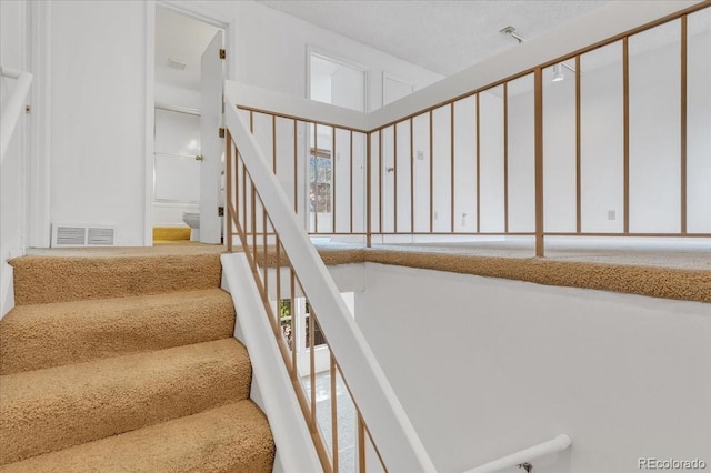 stairs featuring a textured ceiling