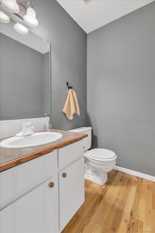 bathroom featuring toilet, hardwood / wood-style flooring, and vanity