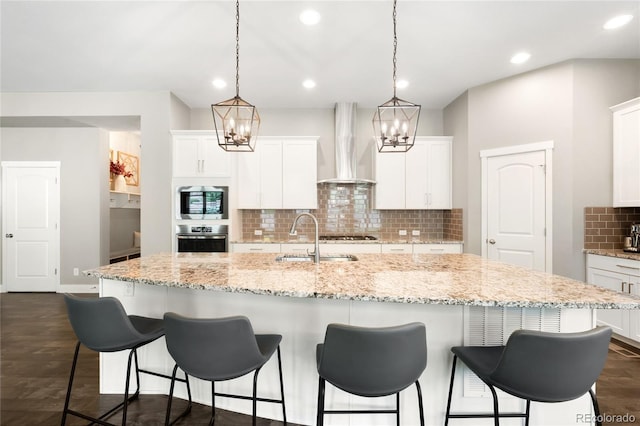 23421 E Rockinghorse Pkwy, Aurora, CO 80016 - kitchen featuring wall chimney range hood, appliances with stainless steel finishes, a chandelier, tasteful backsplash, and white cabinetry