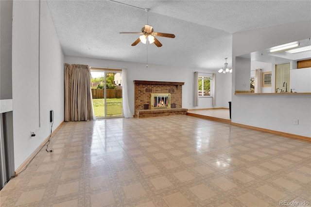 unfurnished living room with ceiling fan, a textured ceiling, healthy amount of natural light, a fireplace, and baseboards