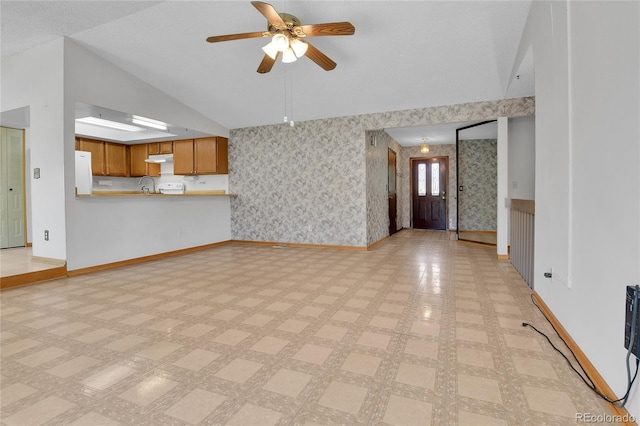 unfurnished living room featuring baseboards, vaulted ceiling, wallpapered walls, a ceiling fan, and a sink
