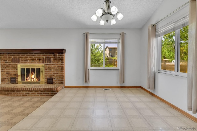 unfurnished living room featuring a chandelier, plenty of natural light, tile patterned floors, a textured ceiling, and baseboards