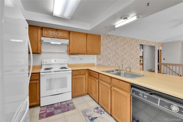 kitchen with white appliances, under cabinet range hood, a sink, light countertops, and light floors