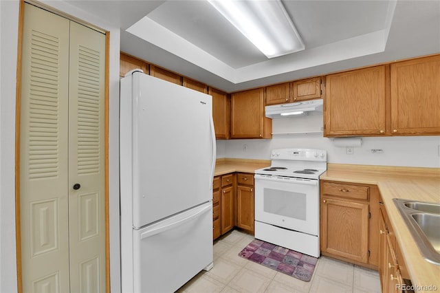 kitchen featuring white appliances, under cabinet range hood, light countertops, and light floors