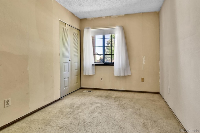 unfurnished bedroom featuring carpet floors, a textured ceiling, a closet, and baseboards
