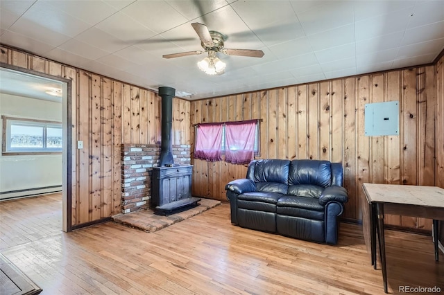 living room with light hardwood / wood-style floors, baseboard heating, and wooden walls