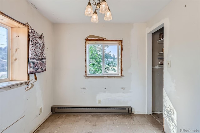 spare room featuring baseboard heating and an inviting chandelier