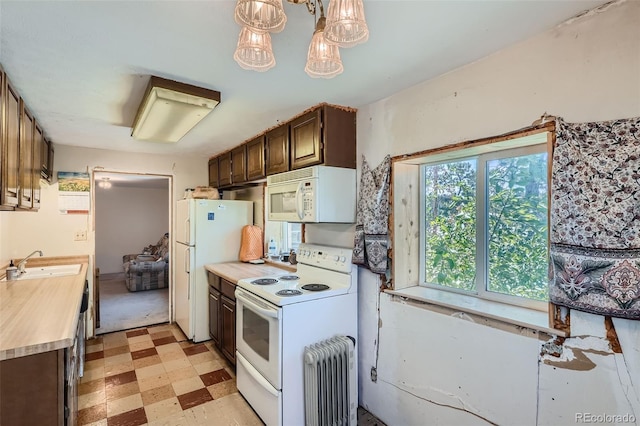 kitchen featuring dark brown cabinets, radiator, pendant lighting, sink, and white appliances