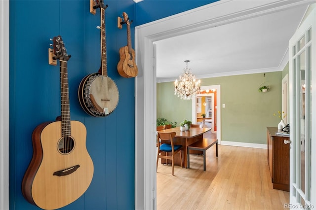 corridor featuring a notable chandelier, crown molding, and light hardwood / wood-style flooring