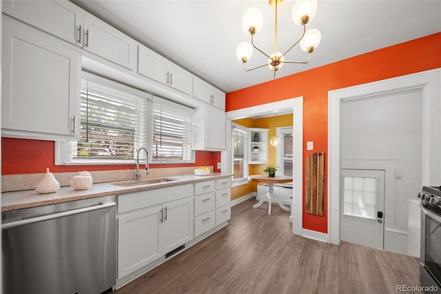 kitchen featuring stainless steel appliances, sink, white cabinets, and decorative light fixtures