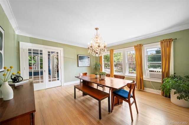 dining room featuring crown molding, an inviting chandelier, light hardwood / wood-style floors, and french doors