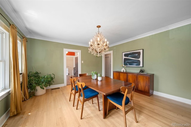 dining room with crown molding, a chandelier, and light wood-type flooring