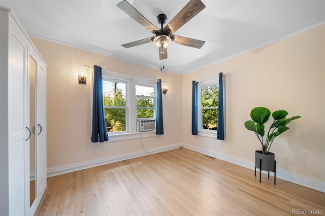 empty room featuring cooling unit, ceiling fan, ornamental molding, and light hardwood / wood-style flooring