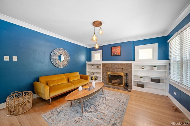 living area featuring a fireplace with flush hearth, wood finished floors, baseboards, visible vents, and ornamental molding