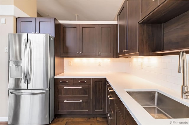 kitchen with tasteful backsplash, dark hardwood / wood-style flooring, stainless steel fridge, and sink