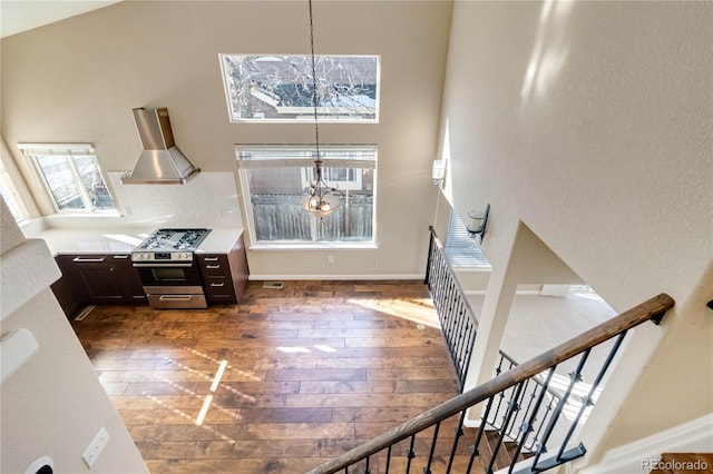 interior space with gas range, hanging light fixtures, dark hardwood / wood-style flooring, range hood, and a notable chandelier