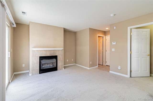 unfurnished living room featuring a wealth of natural light, a tiled fireplace, and light carpet