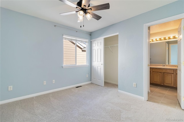 unfurnished bedroom with connected bathroom, ceiling fan, sink, light carpet, and a closet