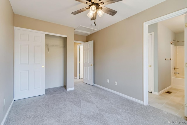 unfurnished bedroom with a closet, ceiling fan, ensuite bathroom, and light carpet