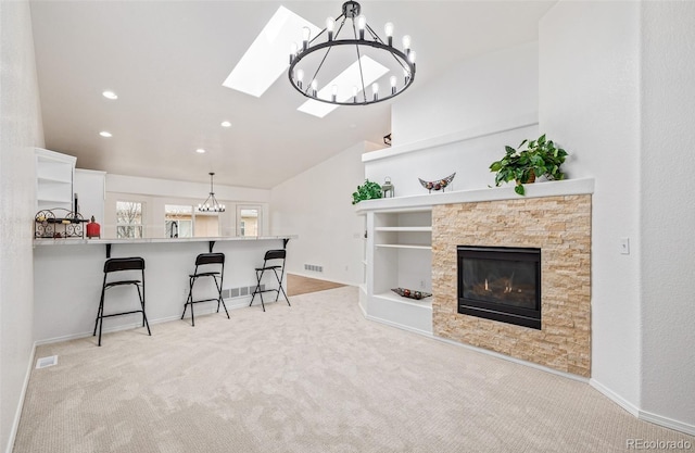 carpeted living room featuring vaulted ceiling with skylight and a fireplace