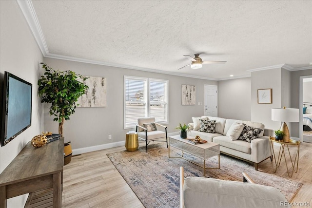 living room with a textured ceiling, light hardwood / wood-style flooring, ceiling fan, and ornamental molding