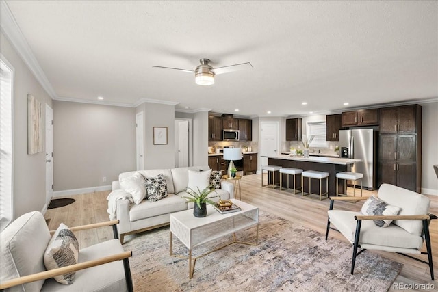 living room with ceiling fan, crown molding, and light wood-type flooring