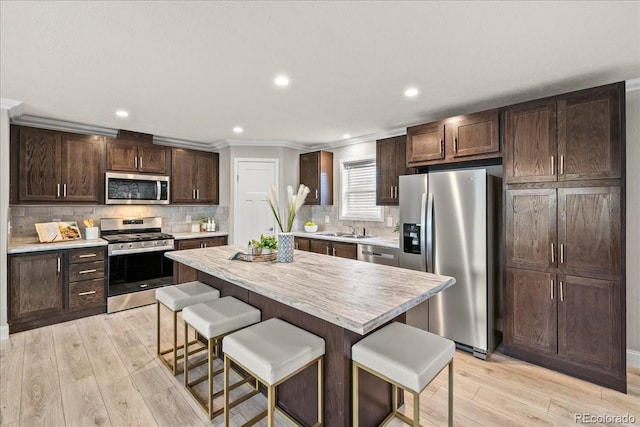 kitchen featuring backsplash, a kitchen breakfast bar, sink, appliances with stainless steel finishes, and a kitchen island