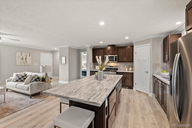 kitchen featuring a center island, tasteful backsplash, a kitchen breakfast bar, light hardwood / wood-style flooring, and appliances with stainless steel finishes