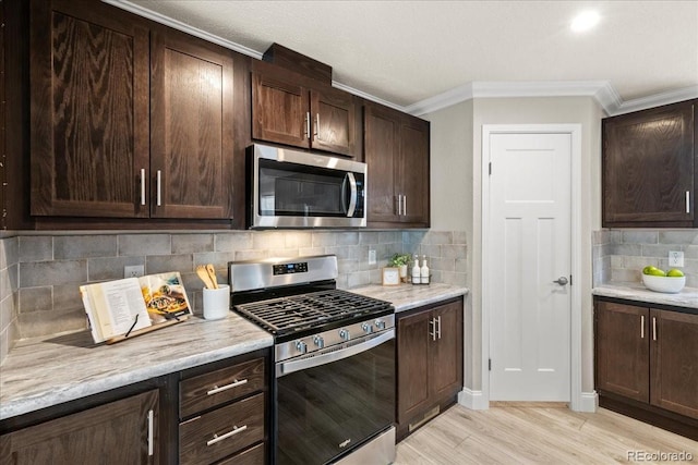 kitchen with decorative backsplash, appliances with stainless steel finishes, dark brown cabinetry, and light stone counters