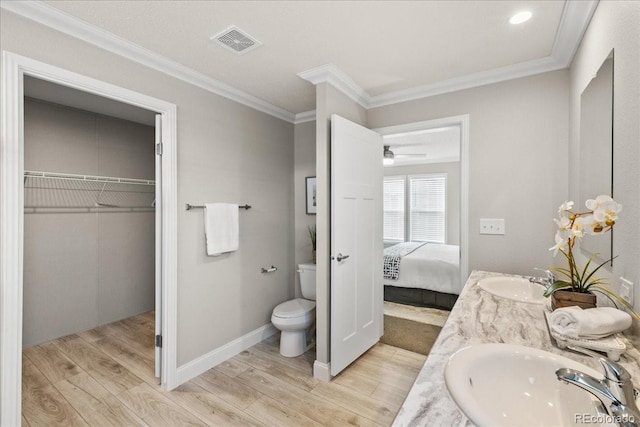 bathroom with ornamental molding, vanity, ceiling fan, wood-type flooring, and toilet