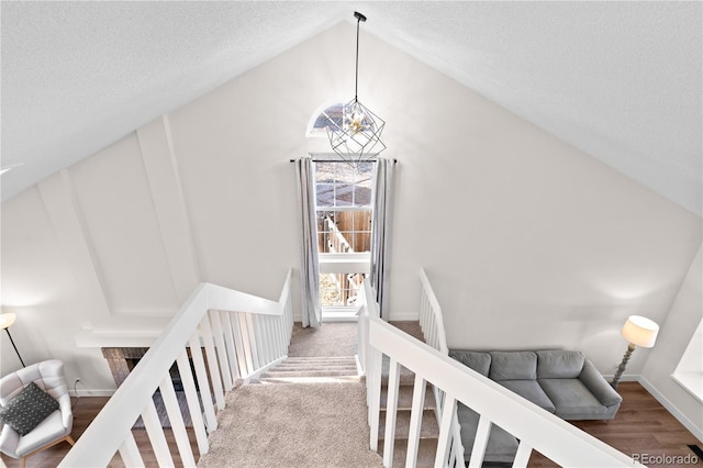 stairway with a textured ceiling and lofted ceiling