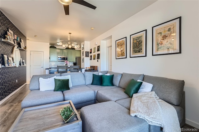 living room with ceiling fan with notable chandelier and wood-type flooring