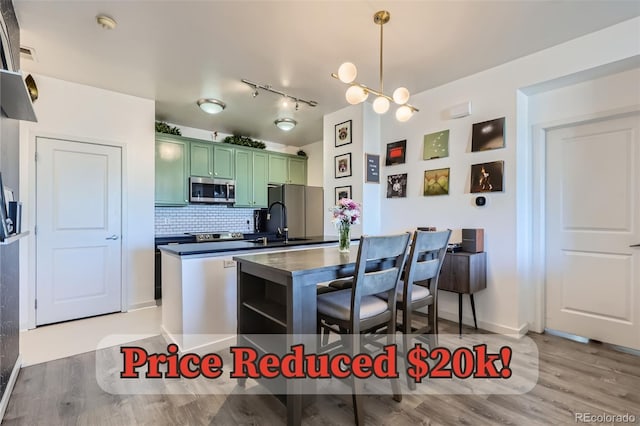 4100 Albion St Unit 221, Denver, CO 80216 - kitchen with stainless steel appliances, green cabinets, light wood-style floors, dark countertops, and tasteful backsplash