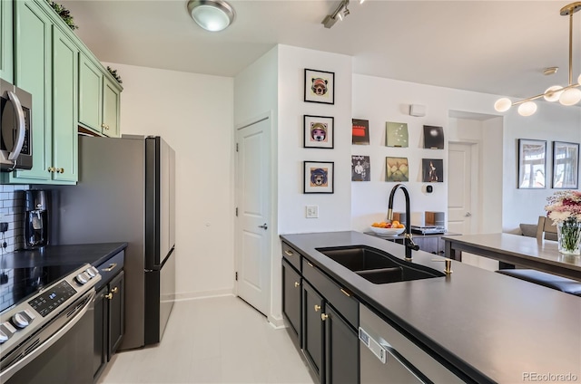 4100 Albion St Unit 221, Denver, CO 80216 - kitchen featuring green cabinetry, a sink, appliances with stainless steel finishes, backsplash, and dark countertops