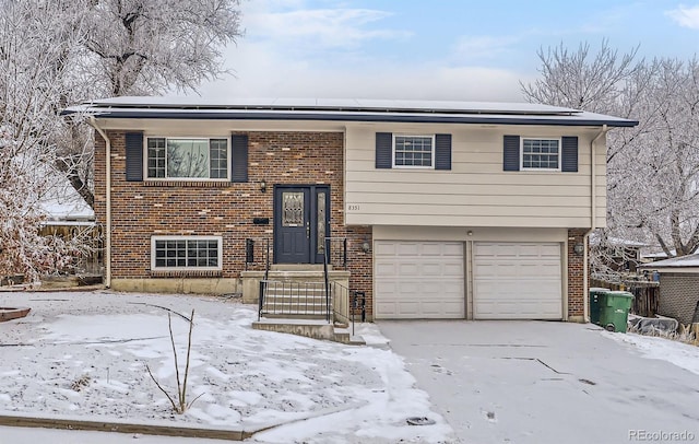 raised ranch featuring a garage and brick siding