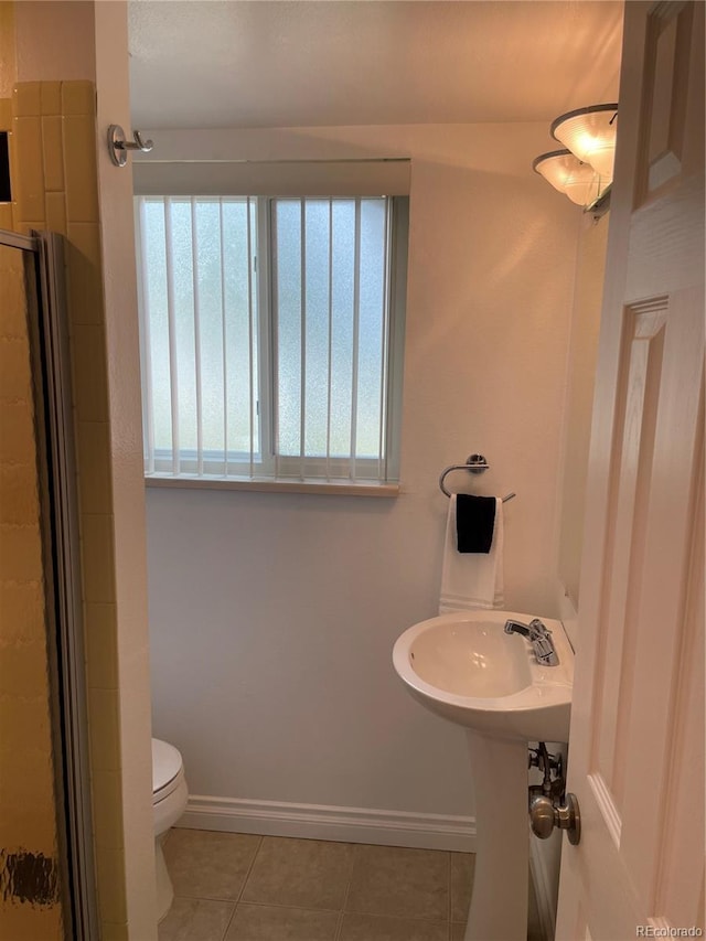 bathroom with a shower with shower door, toilet, and tile patterned floors