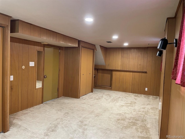 basement featuring wooden walls and light colored carpet