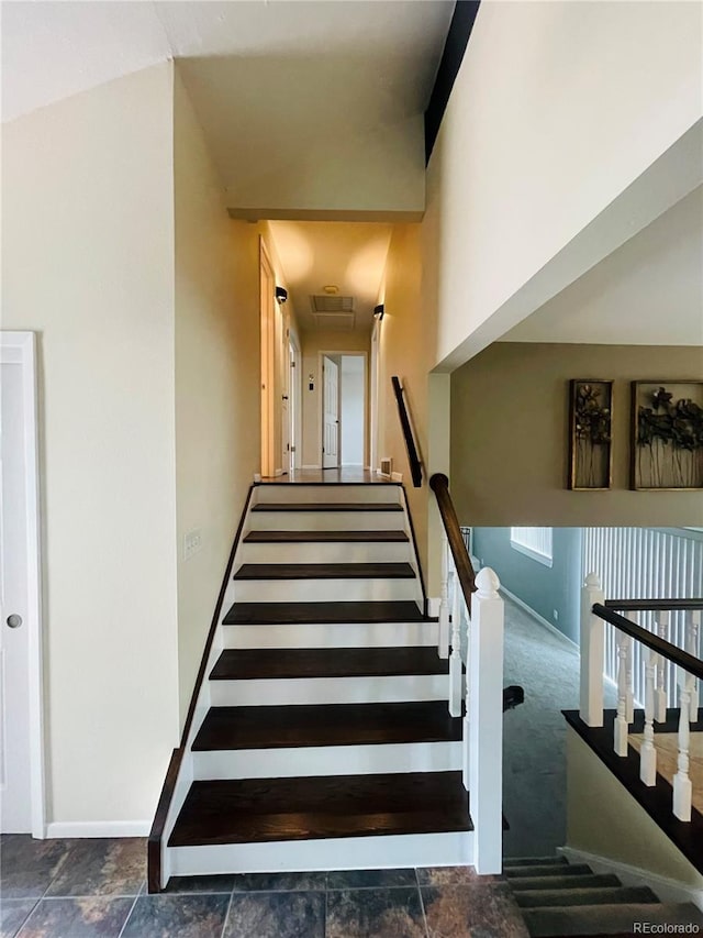 stairway featuring lofted ceiling and carpet