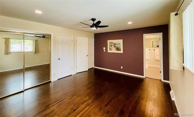 unfurnished bedroom featuring ceiling fan, two closets, dark hardwood / wood-style floors, and ensuite bathroom