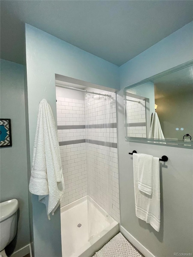 bathroom featuring a tile shower and toilet