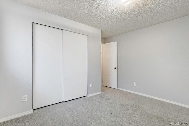 unfurnished bedroom with light carpet, a closet, and a textured ceiling